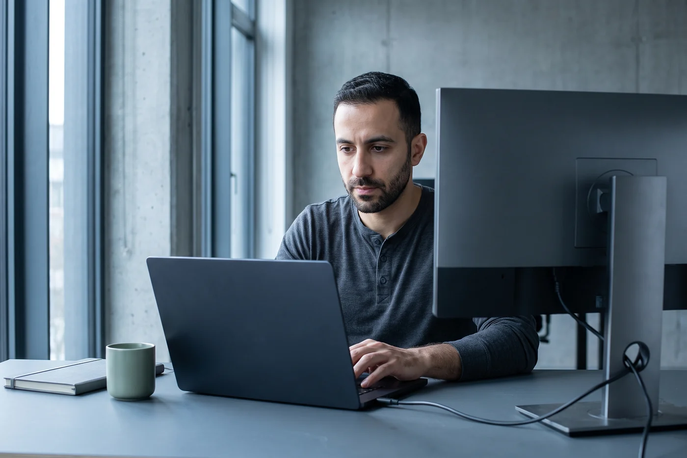 A software engineer operating a development environment at a laptop and an external monitor