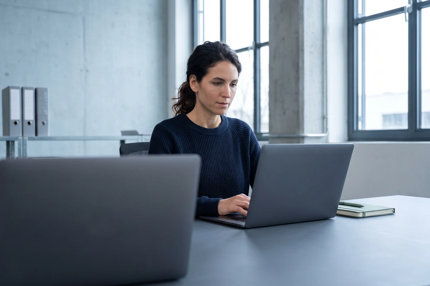 An engineering lead writing architecture notes at a laptop